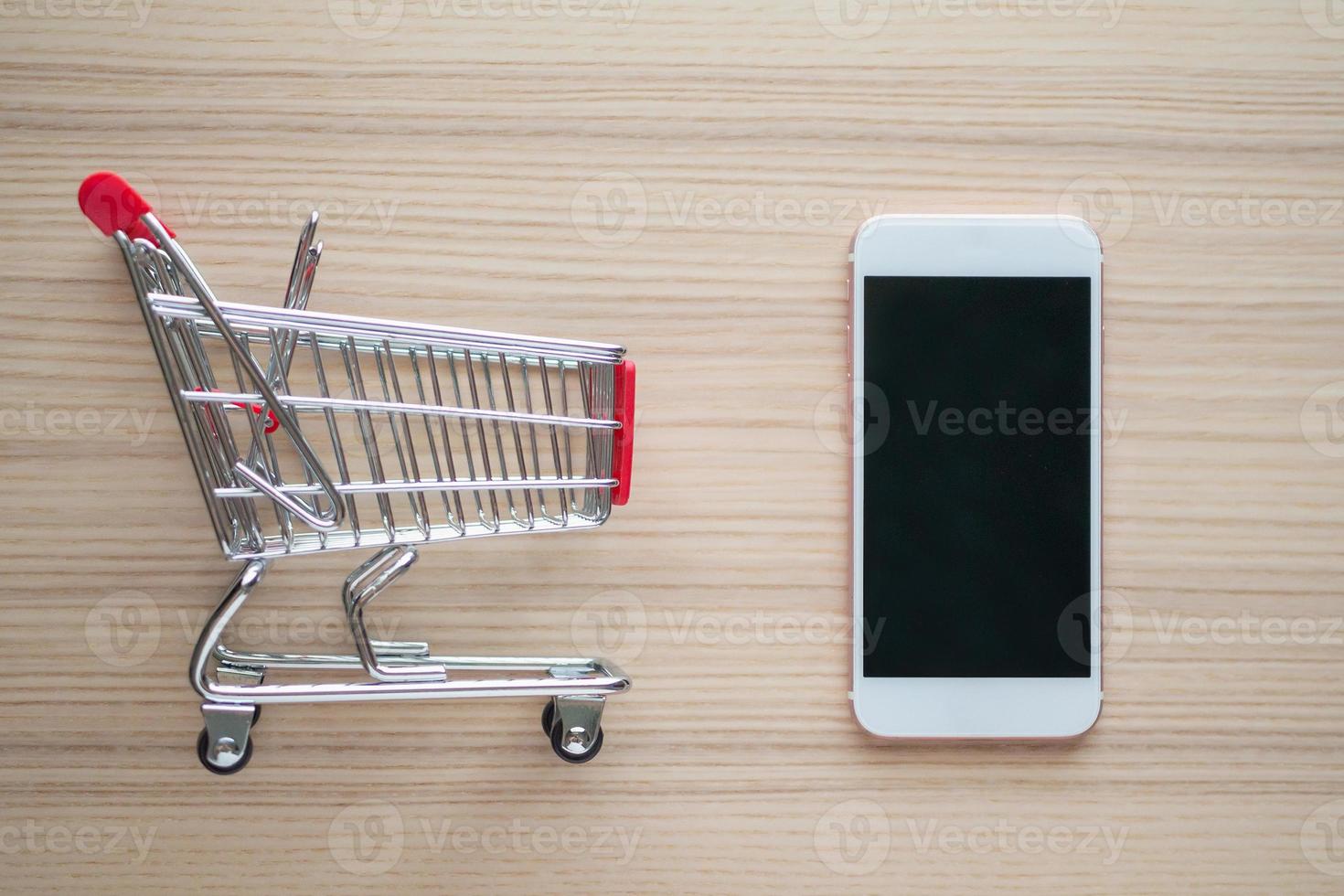 Mobile phone with shopping cart on wood table background shopping online concept photo