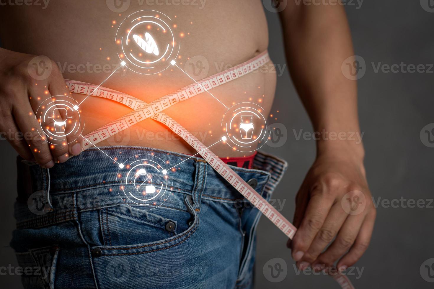 Closeup shot of asian man measuring tape wear jean trousers related vector icon orange light, planning exercise and loss weight for good health in the feature, healthcare and gym concept copy space photo