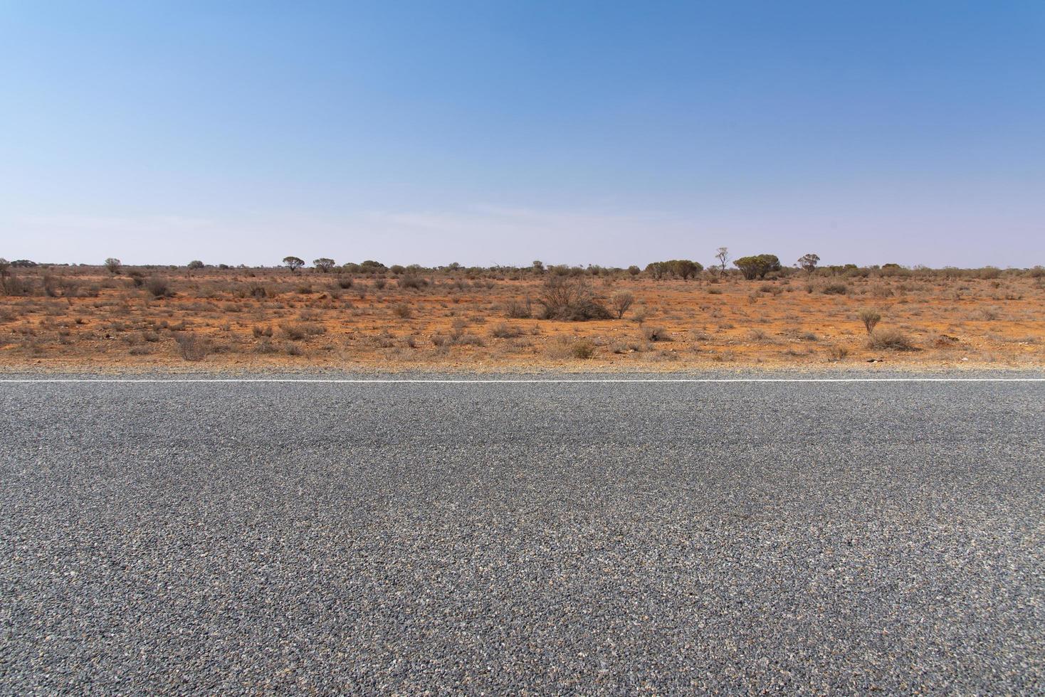 Road view with red dirt at the background and blue sky. photo