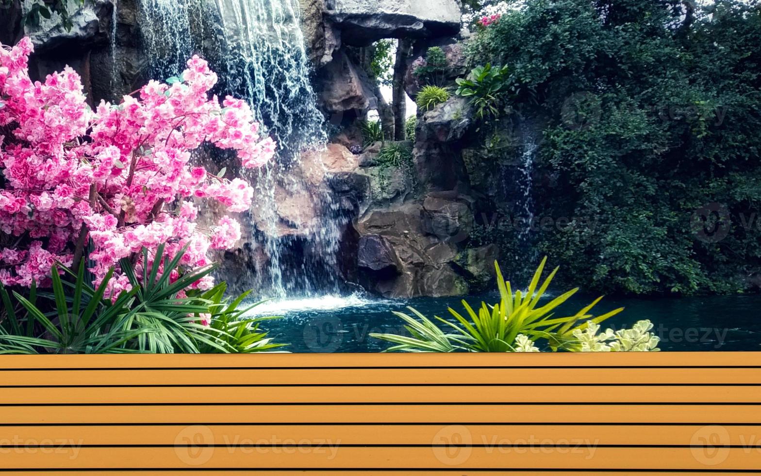 Brown table wooden shelf with pink flowers and waterfall backdrop. photo