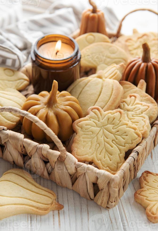 Cookies shaped like pumpkin and leaves on rustic wood background photo