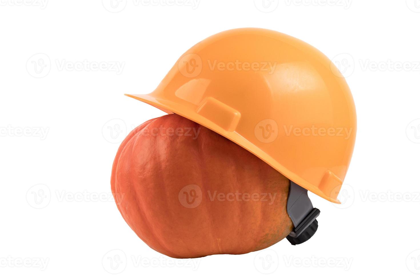 calabaza naranja en un casco de construcción amarillo, sombrero duro sobre un fondo blanco aislado. foto