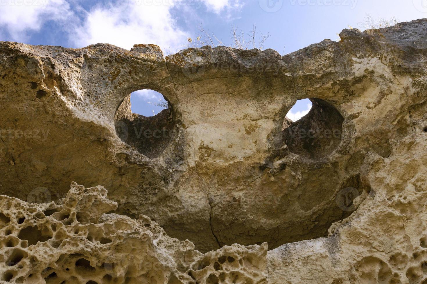 Top of the cliff in the form of a smiling face with eyes and a mouth. Texture, weathered limestone background. The bottom of the ancient sea. Abstract background. photo