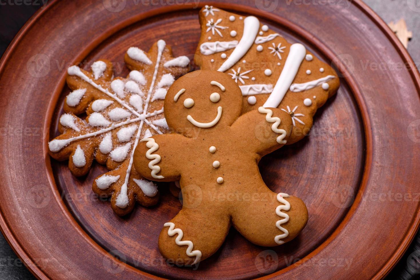 Beautiful gingerbread on a brown ceramic plate with Christmas tree decorations on a dark concrete background photo