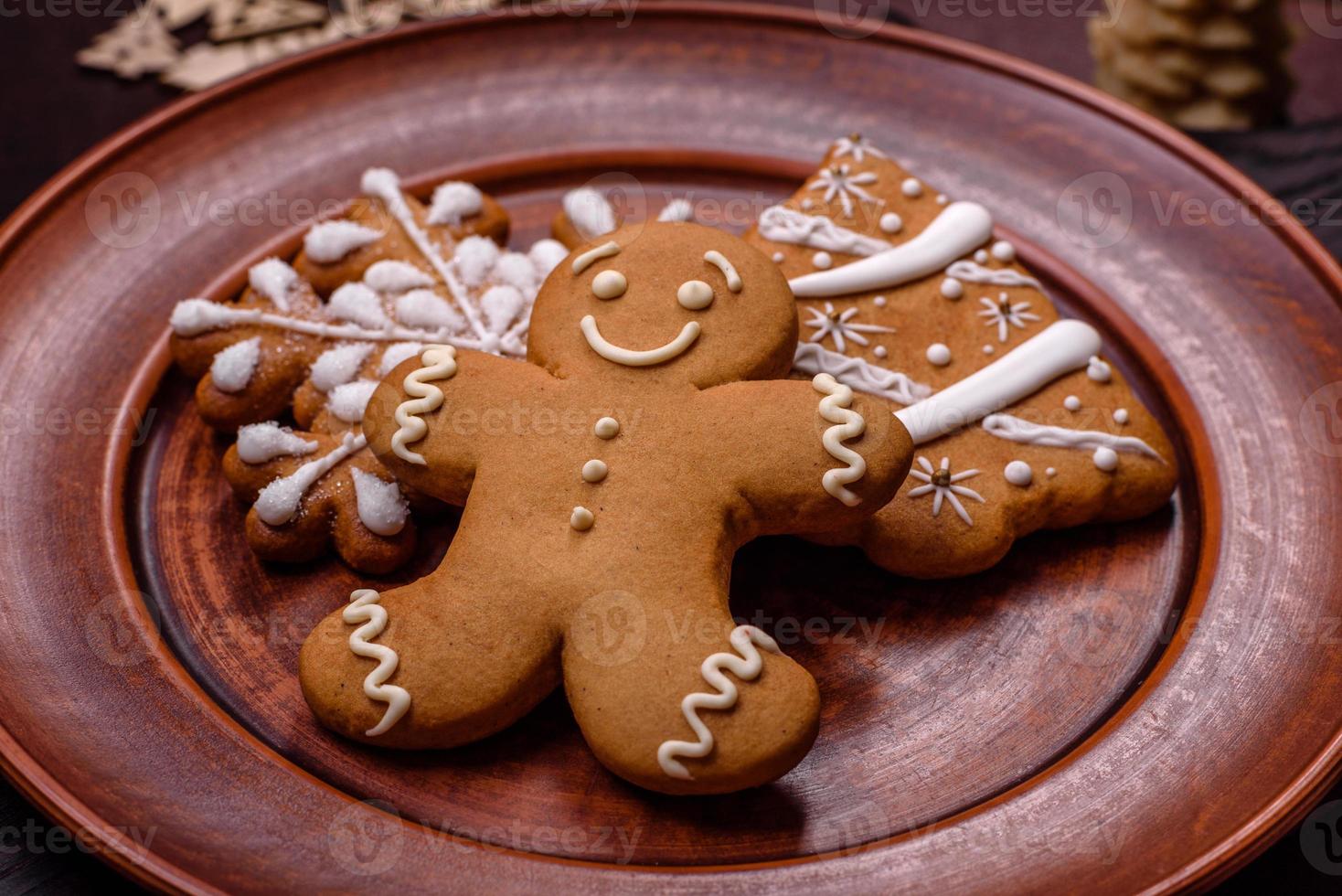 Beautiful gingerbread on a brown ceramic plate with Christmas tree decorations on a dark concrete background photo