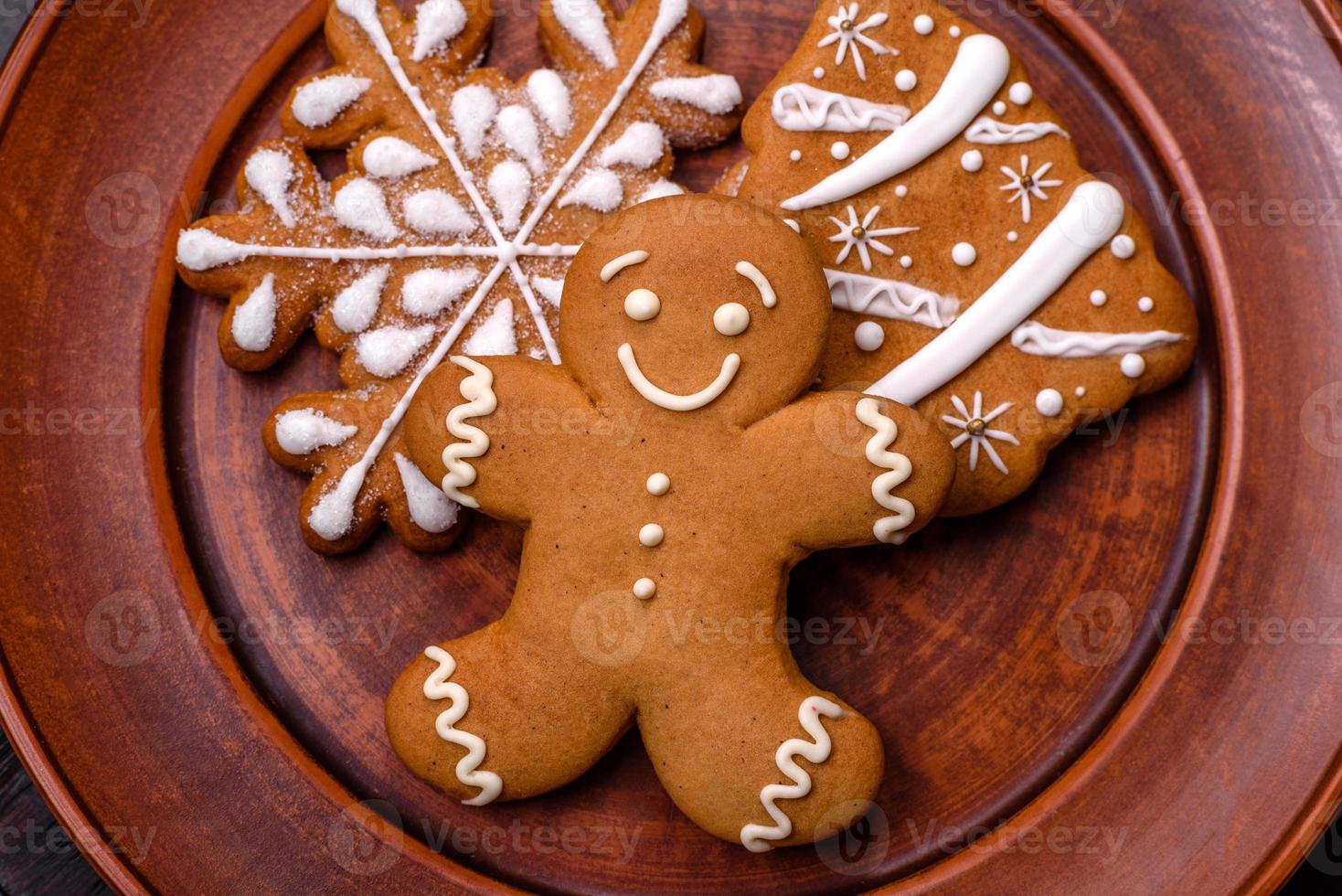 Beautiful gingerbread on a brown ceramic plate with Christmas tree decorations on a dark concrete background photo
