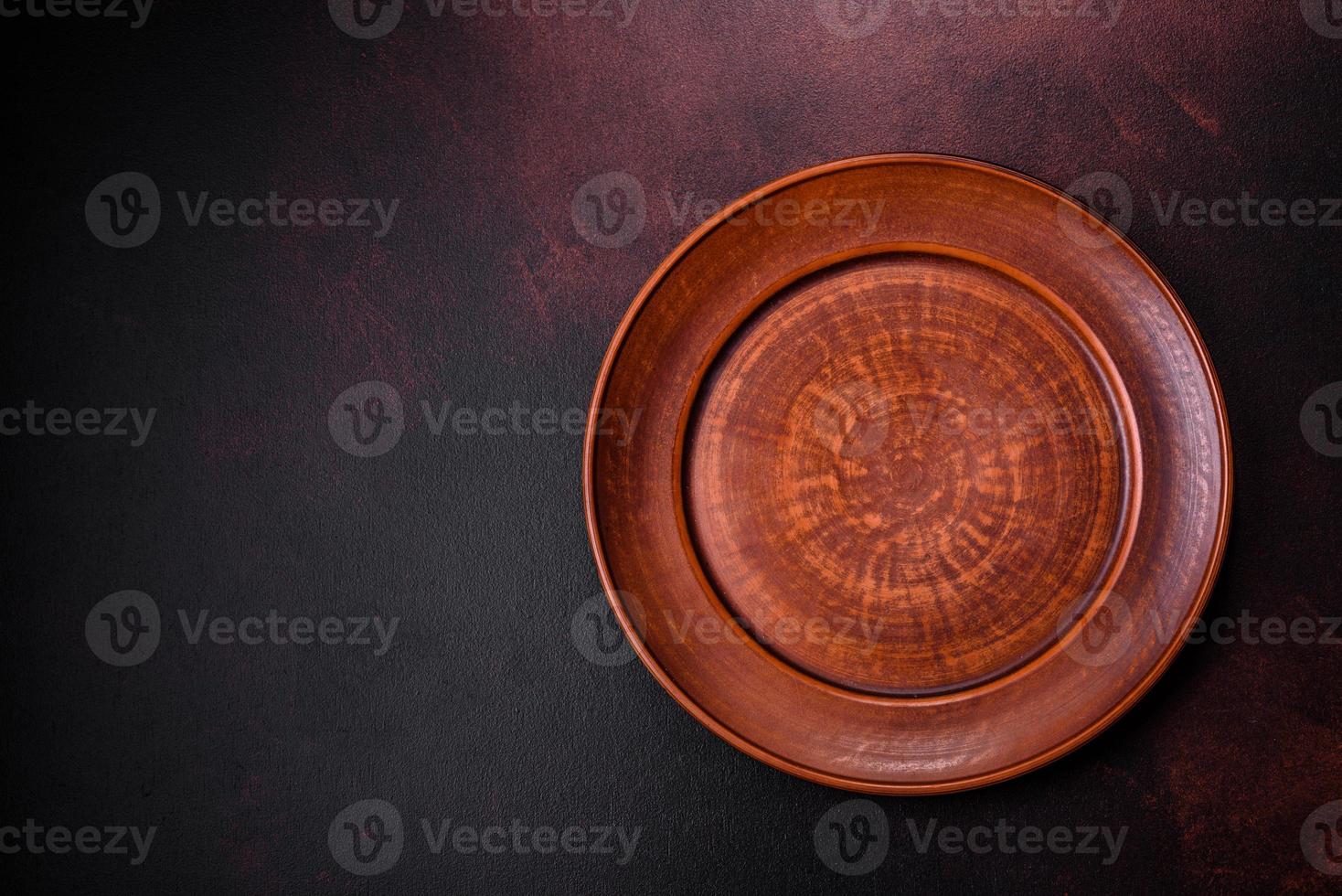 An empty brown ceramic plate on a dark concrete brown background photo