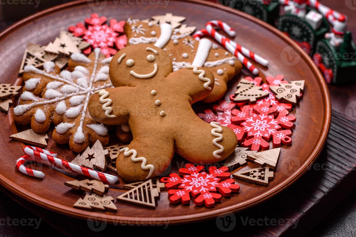 Beautiful gingerbread on a brown ceramic plate with Christmas tree decorations on a dark concrete background photo
