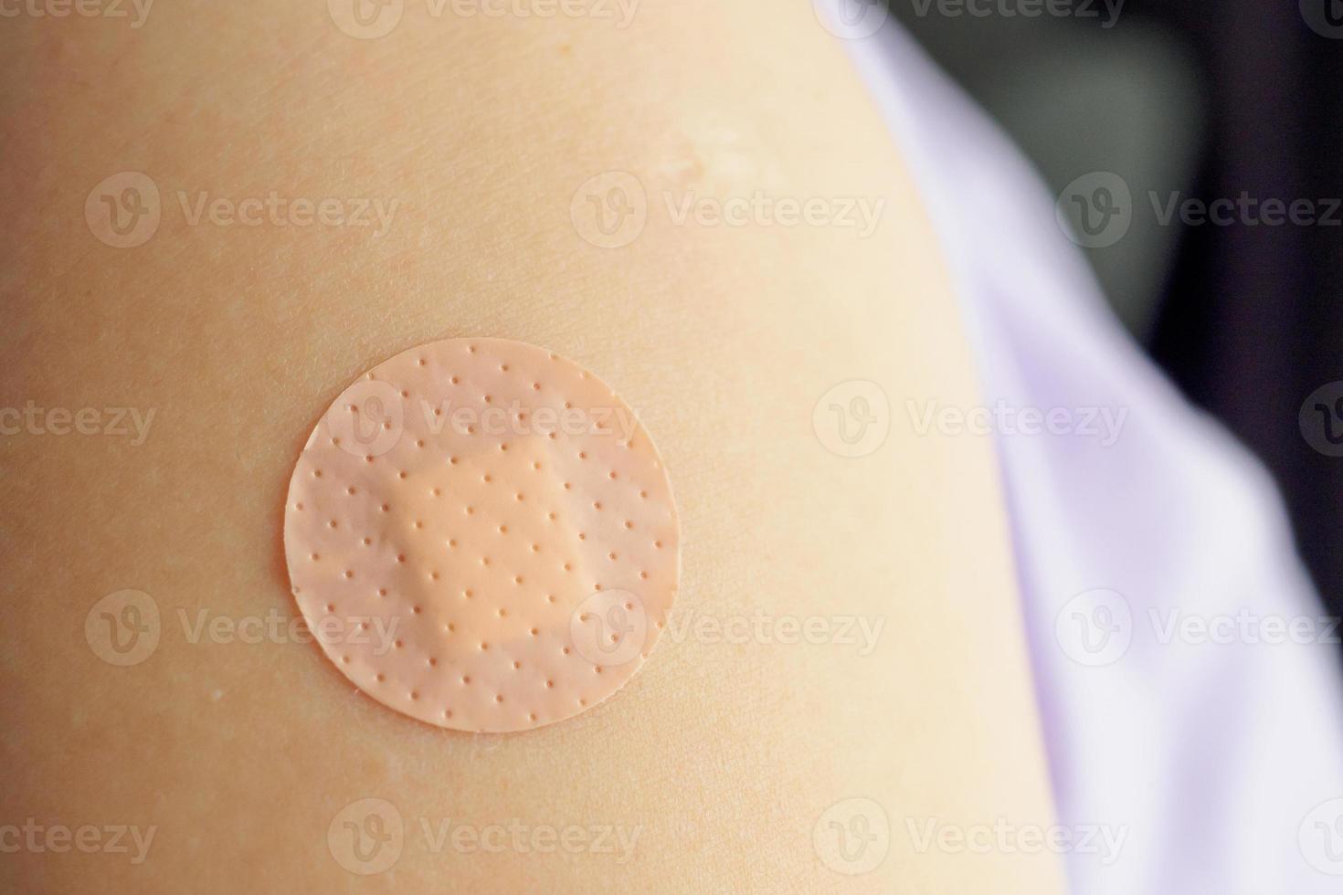 cerrar el vendaje adhesivo marrón circular en el brazo del paciente después de la inyección o vacunación del medicamento foto