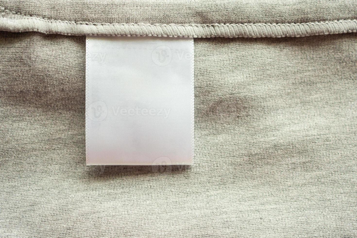 White blank laundry care clothing label on gray fabric texture background photo