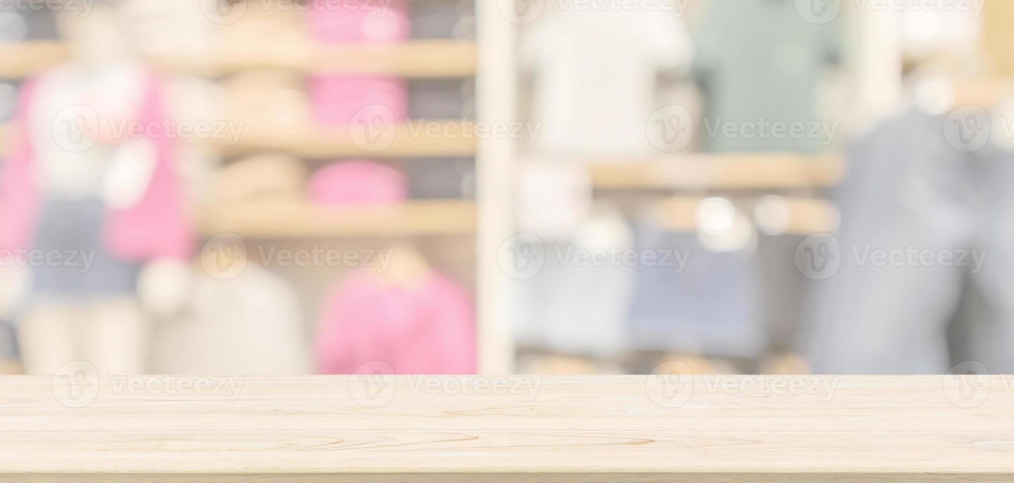 Empty wood table top with modern clothing store interior blur abstract defocused background with bokeh light for product display photo
