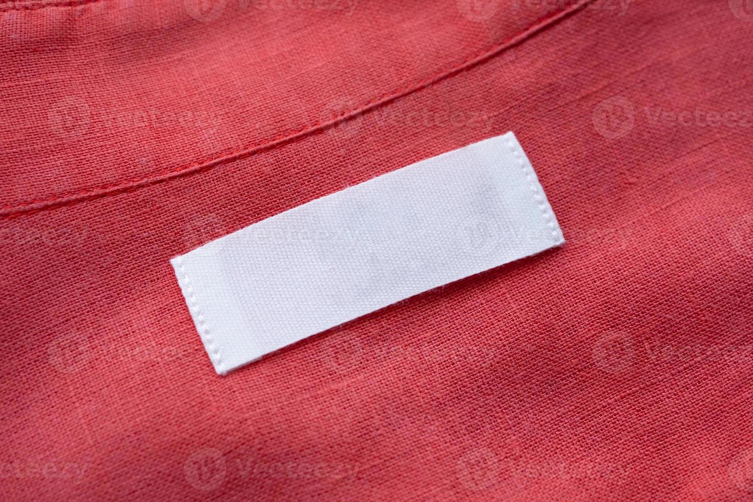 White blank clothing tag label on red linen shirt fabric texture background photo