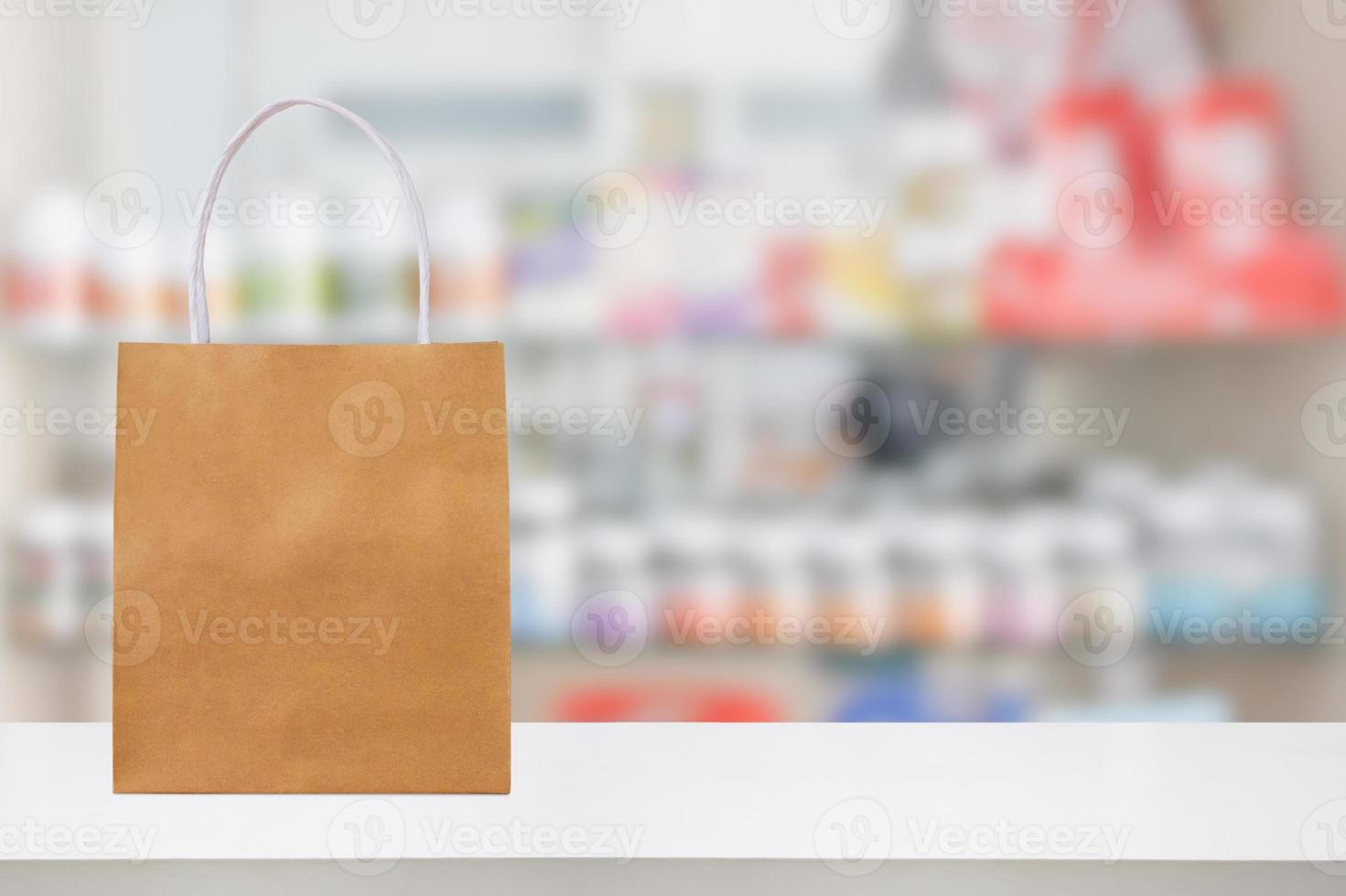 Paper bag on Pharmacy drugstore counter table with medicine and healthcare product on shelves blur background photo