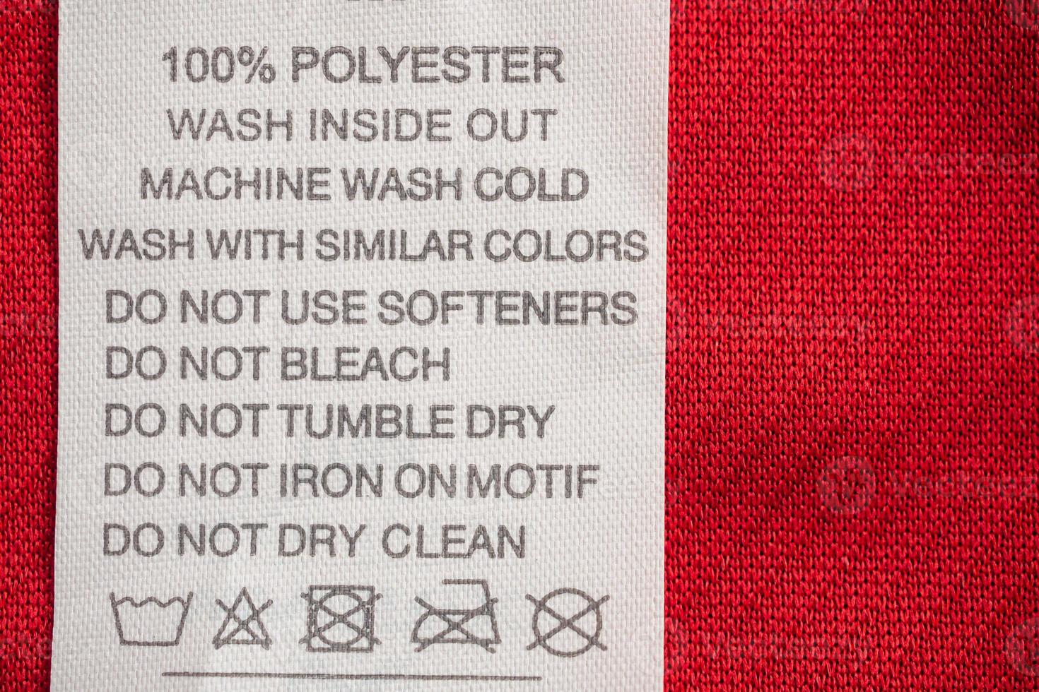 White laundry care washing instructions clothes label on red jersey polyester sport shirt photo