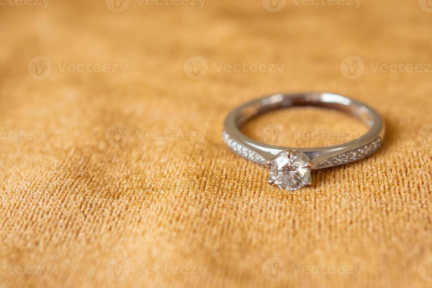 Jewelry diamond ring on golden fabric background close up photo