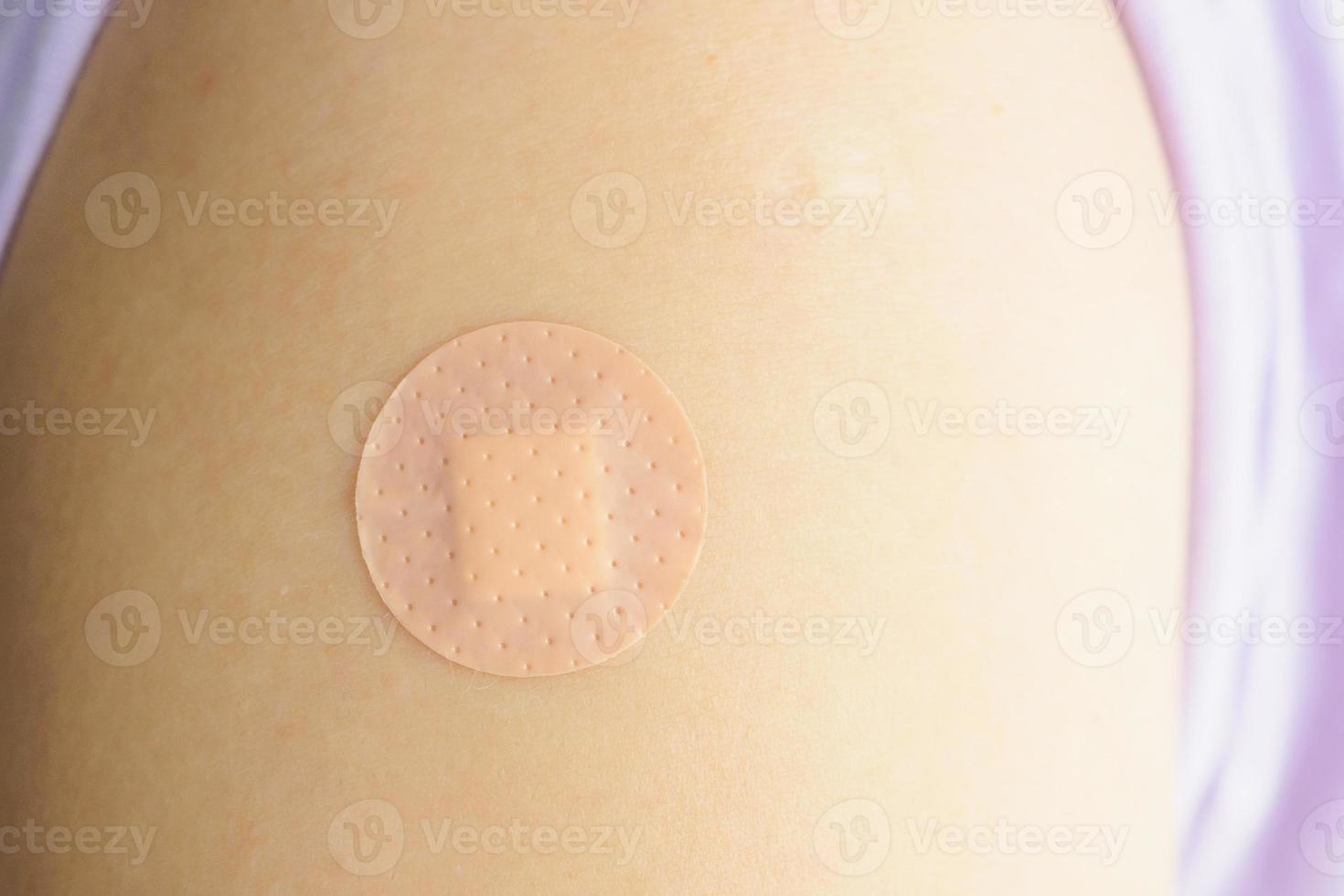 Close up circle brown adhesive bandage on patient arm after medicine injection or vaccination photo
