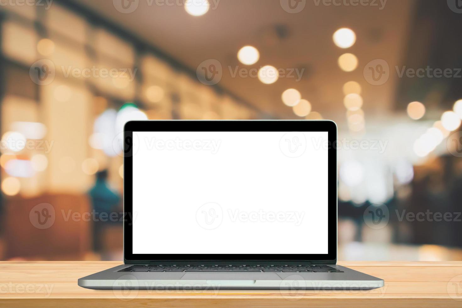 Blank white screen laptop computer on wood table top with cafe restaurant abstract bokeh light defocused blur background photo