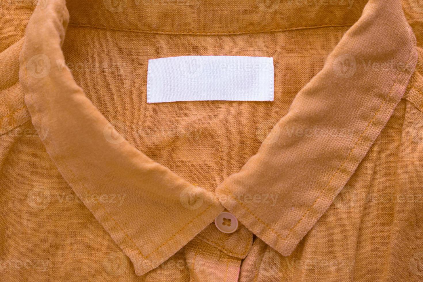 White blank clothing tag label on brown linen shirt fabric texture background photo