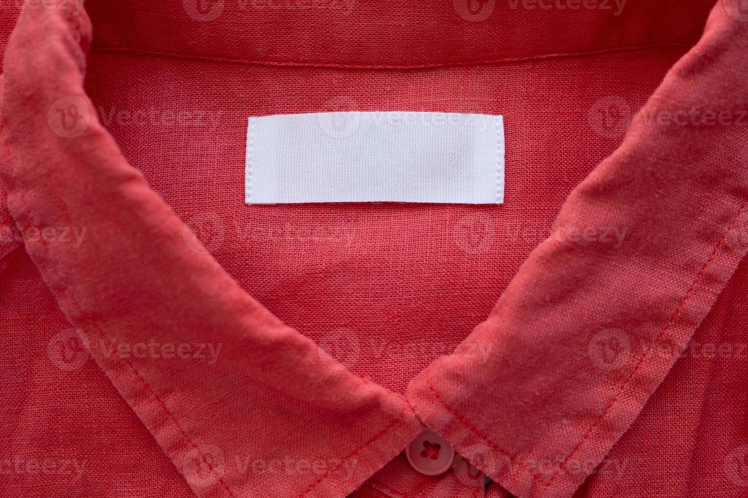 White blank clothing tag label on red linen shirt fabric texture background photo