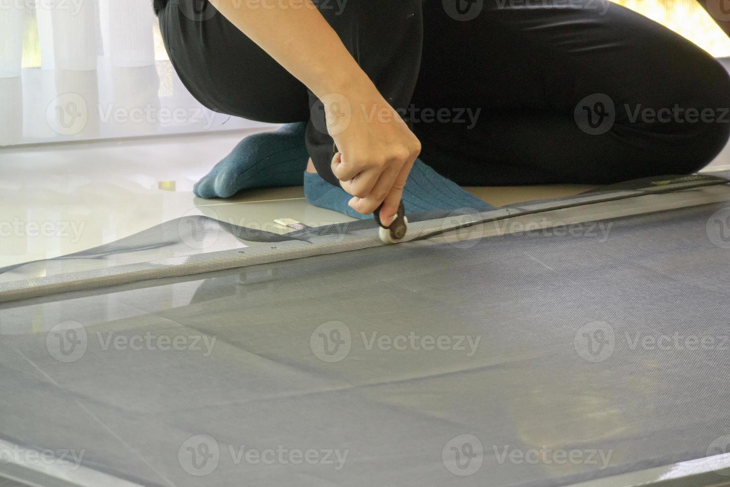 man install mosquito net wire screen on house window protection against insect photo