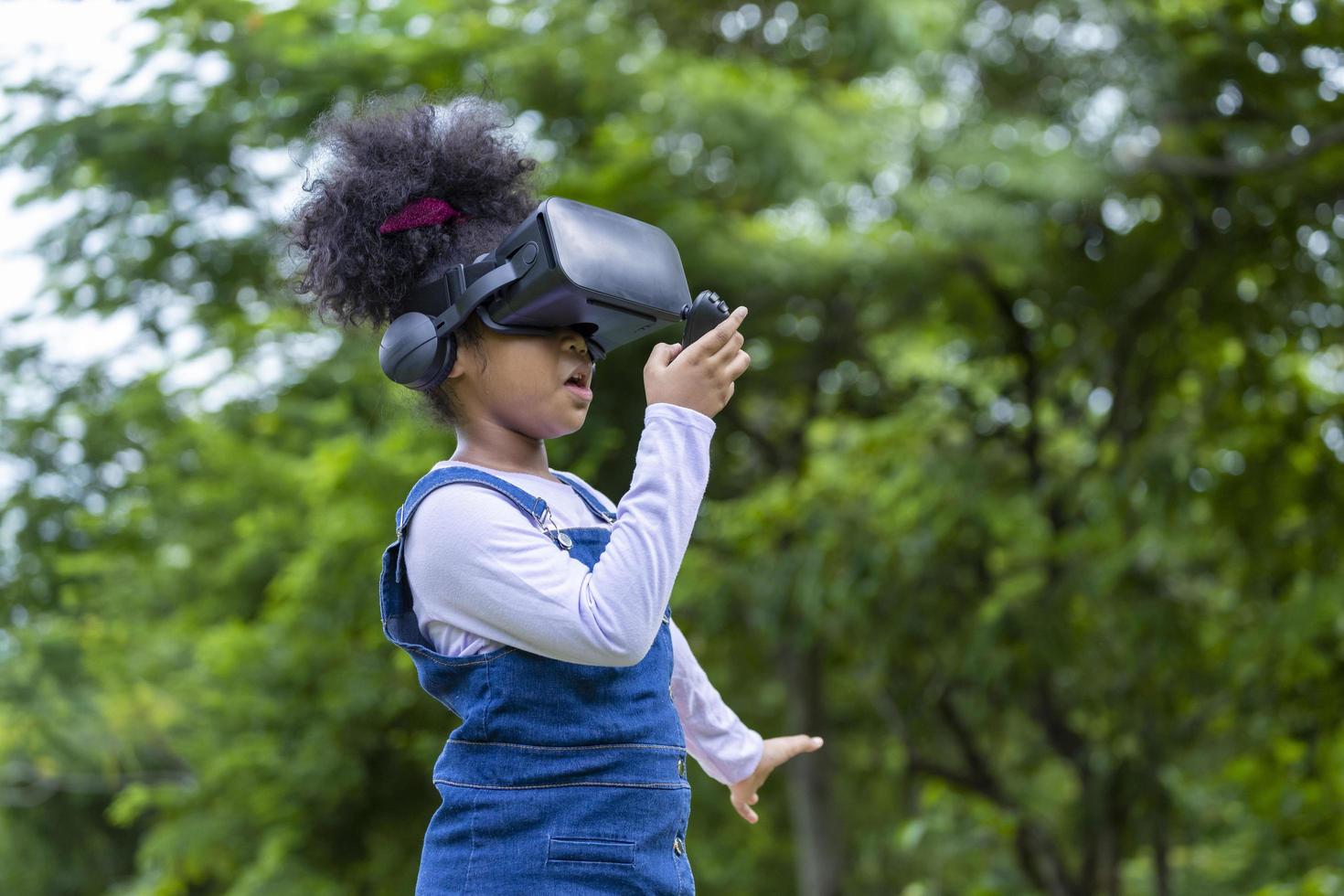 African girl is playing game using vr goggles outdoor in the public park for modern education and gadget with copy space photo