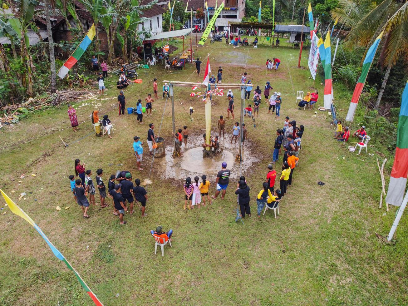 Blitar, Indonesia - September 11, 2022 Aerial view of very happy children taking part in a banana tree climbing competition to get prizes and being seen by many photo