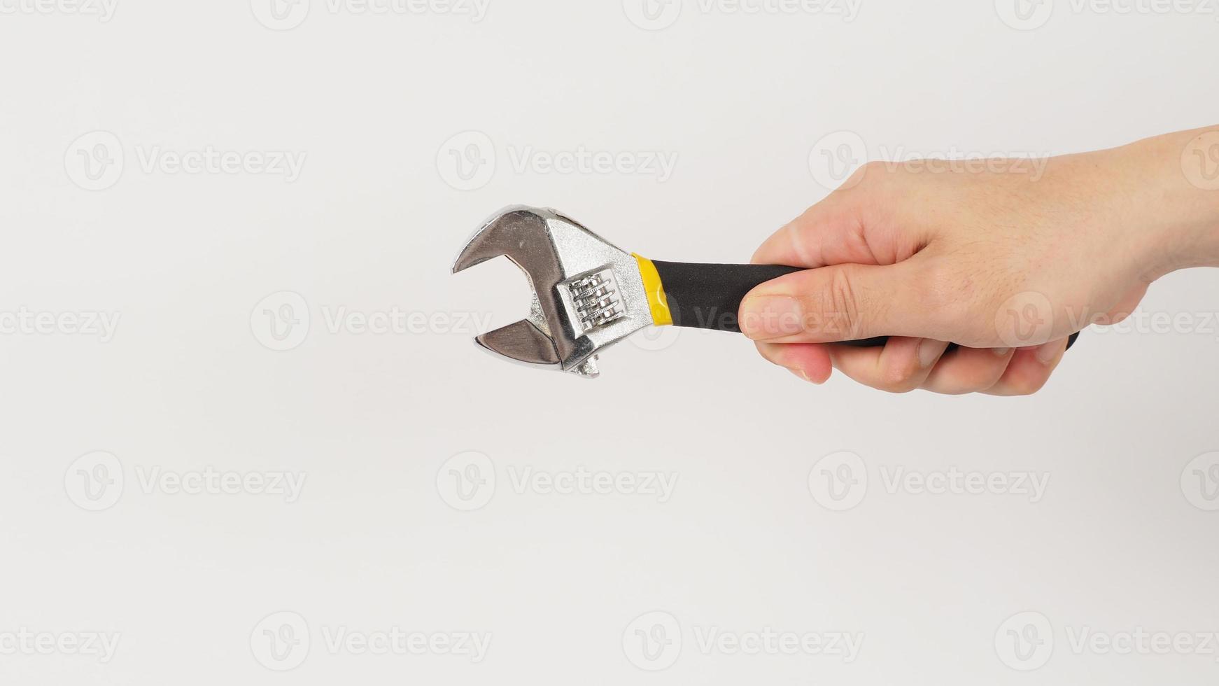 The hand is holding an adjustable wrench isolated on white background. Backhand picture. photo