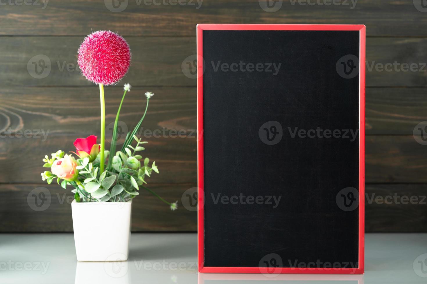 Flower vase and blank chalkboard on table photo