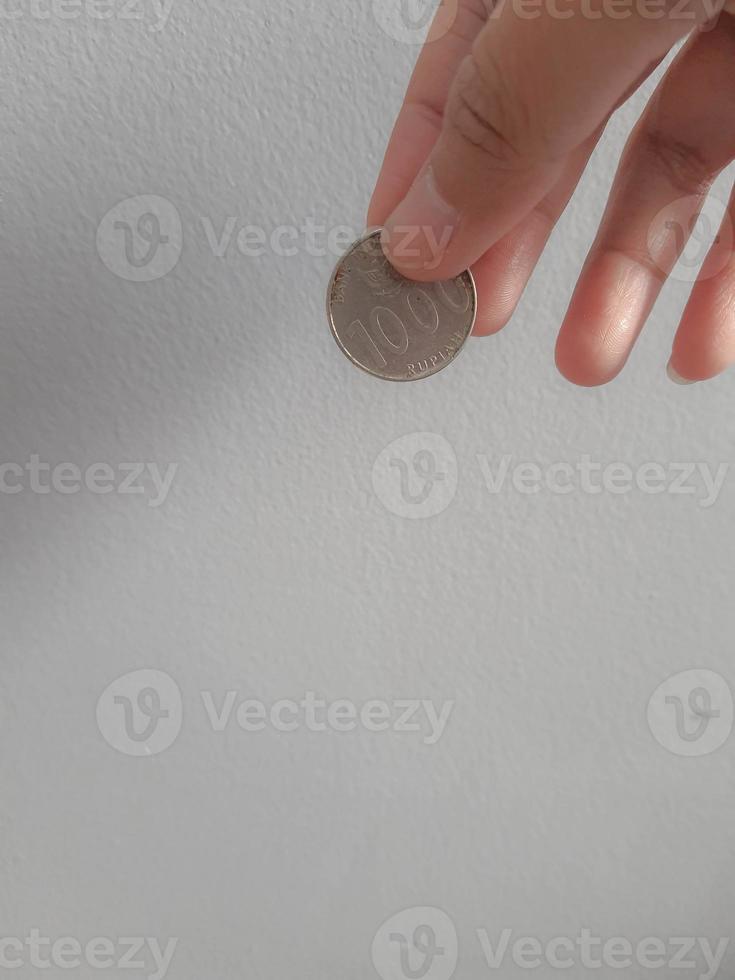Isolated photo of a hand holding a thousand rupiah coin.