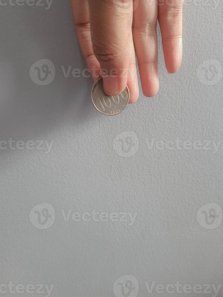 Isolated photo of a hand holding a thousand rupiah coin.