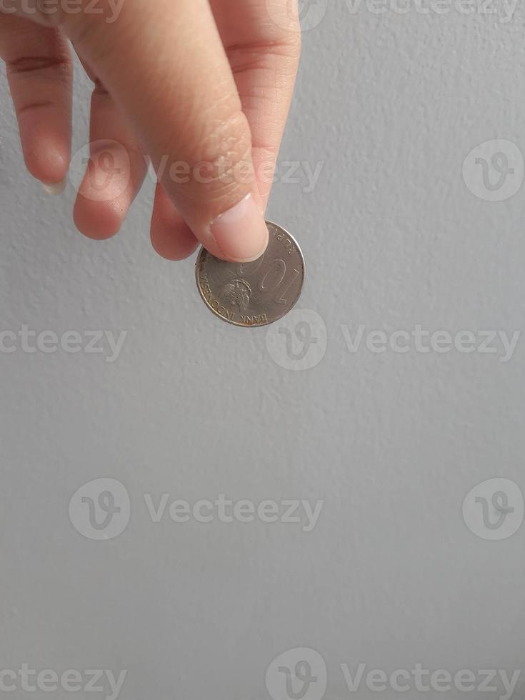 Isolated photo of a hand holding a thousand rupiah coin.