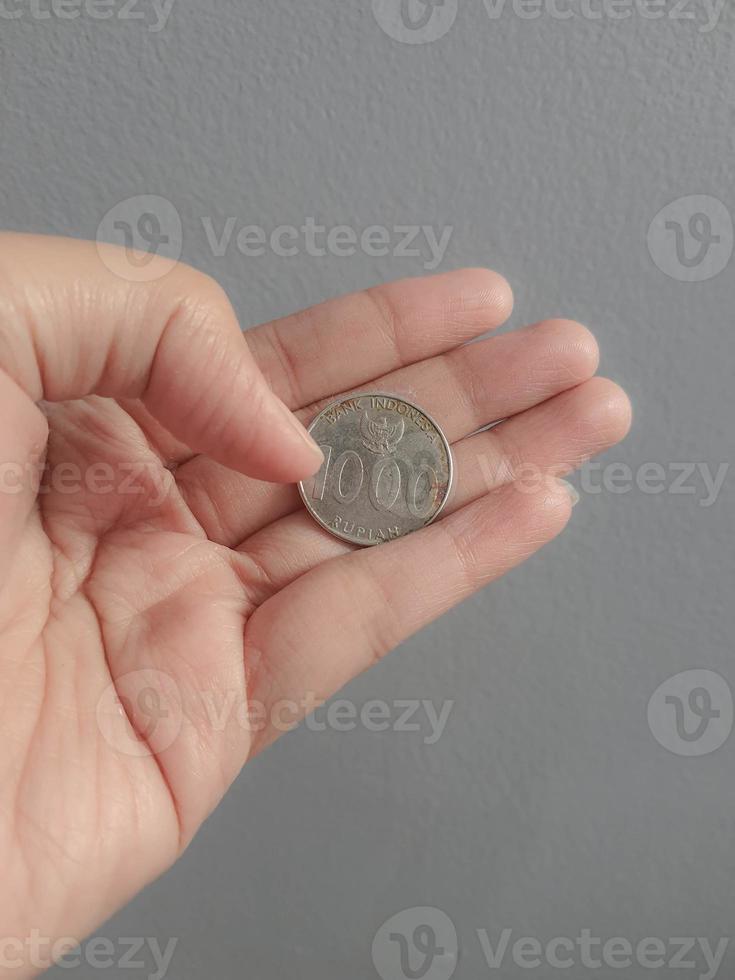 Isolated photo of a hand holding a thousand rupiah coin.