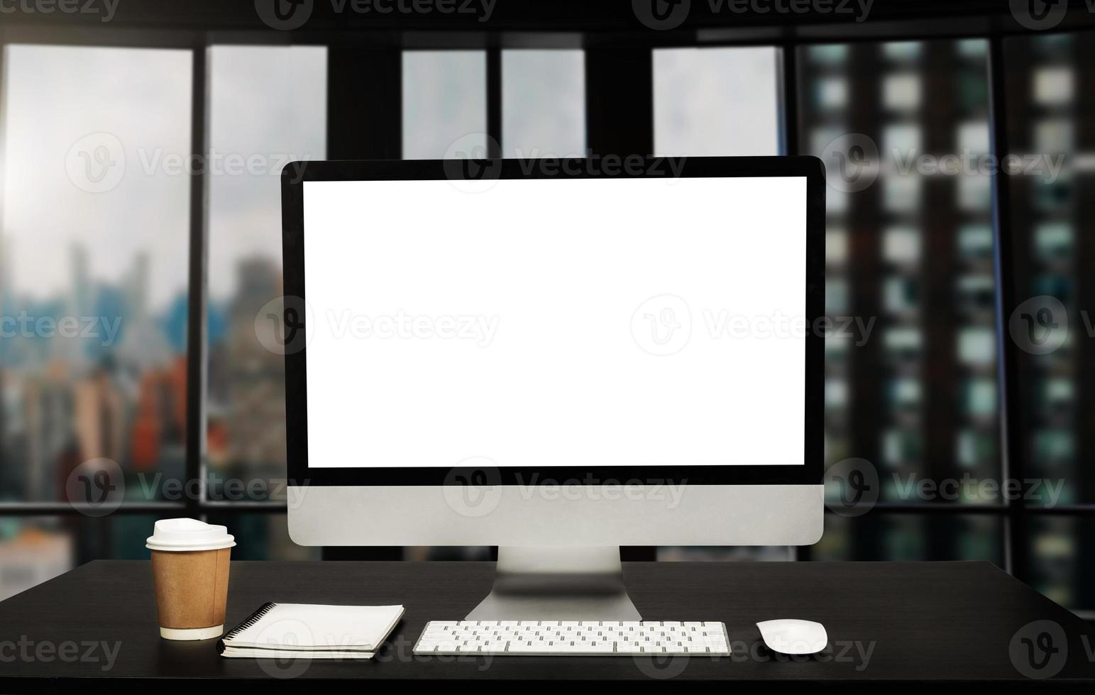 Workspace computer putting on wood working desk and surrounded by coffee cup, clipboard, potted plant, stack of smartphone, tablet, and keyboard  Orderly office photo