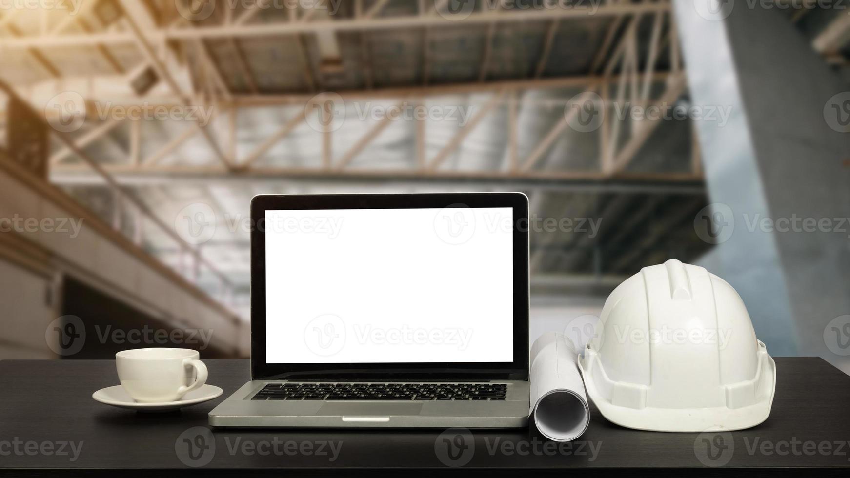 Front view of laptop computer and office construction on table in office blurred background.Architect concept. photo