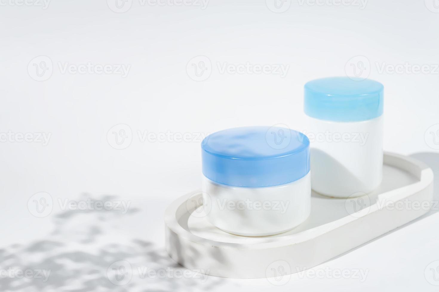 Set of day and night cream jars on a concrete tray on white background with flowers chados. Skin care concept, Mockup photo