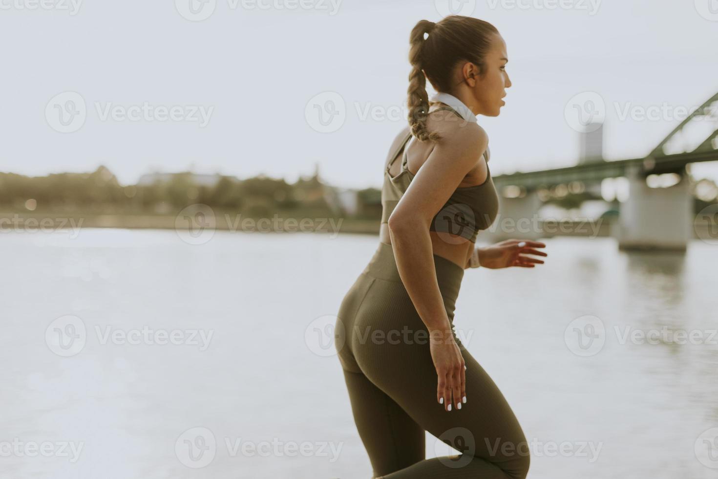 Active young beautiful woman running on the promenade along the riverside photo