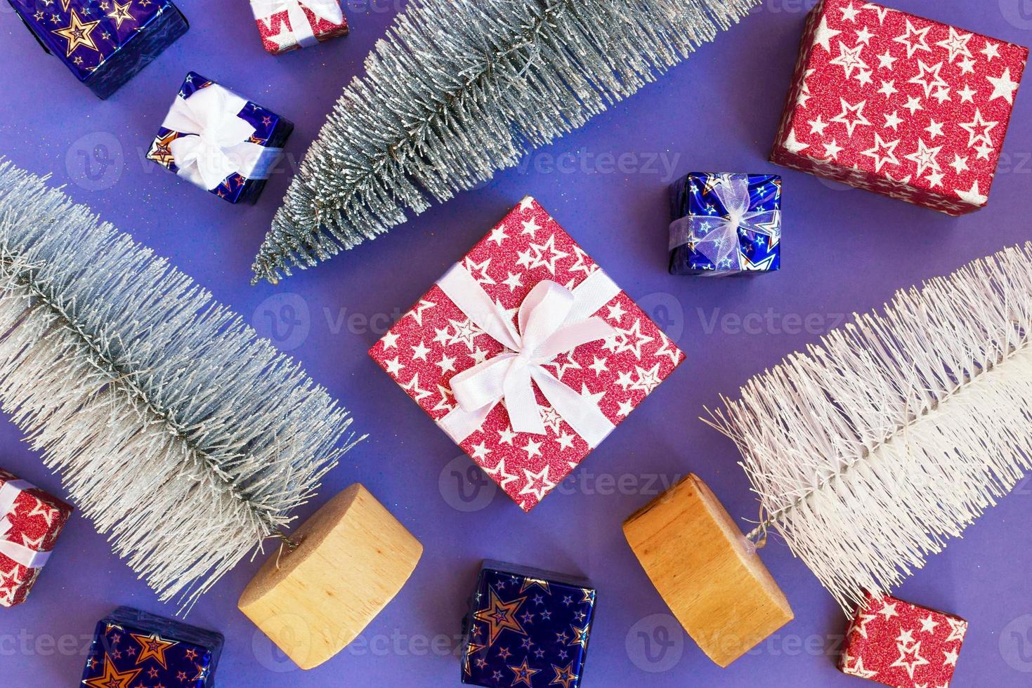 Shiny artificial Christmas trees and gift boxes on purple background, flat lay. Holiday concept for New Year or Christmas. photo