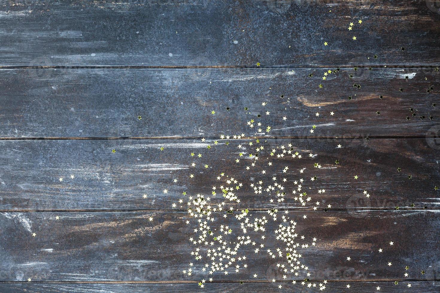 Dark wooden background with golden confetti photo