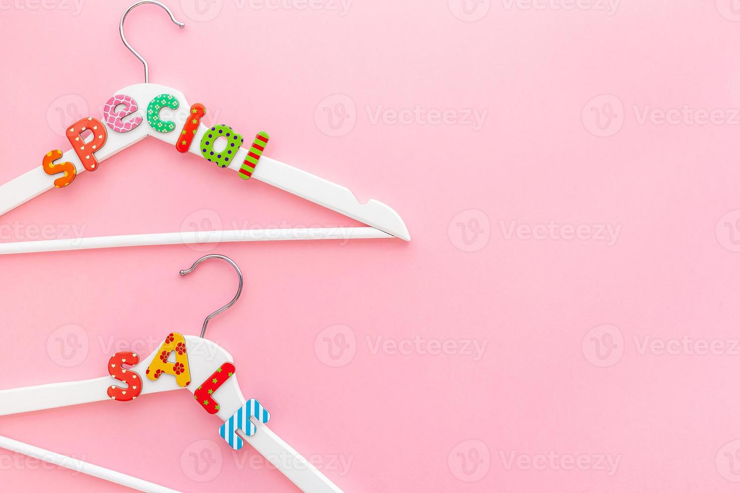 White hangers with sale text on pink background photo