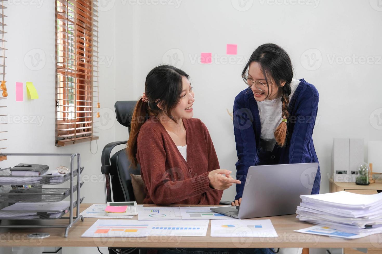 Two young Asian woman discuss investment project working and planning strategy. Business people talking together with laptop computer at home. photo