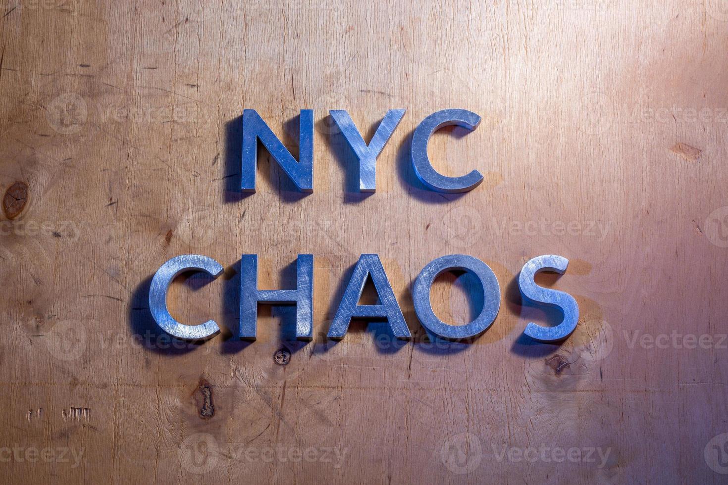 The words NYC chaos laid with metal letters on flat plywood surface under white and blue police lights. Concept. photo