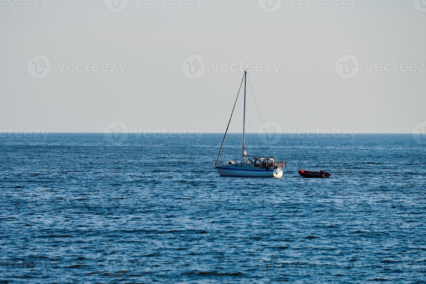 barco de vela flotando en un mar azul tranquilo en verano, clima tranquilo, fondo de cielo despejado, aventura foto