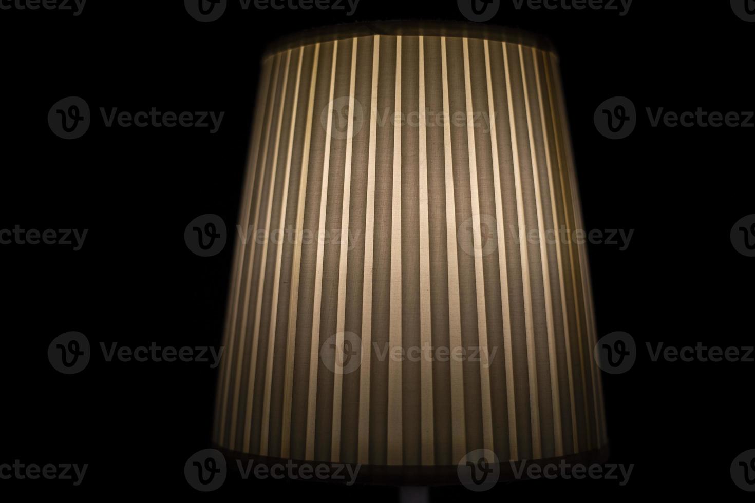 Lampshade lamp. Lamp is in dark. Light on black background. Ribbed paper. photo