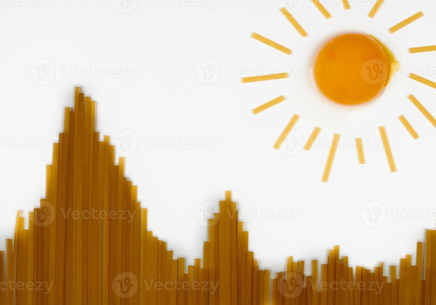 Uncooked spaghetti in shape of hills and egg as sun. Travel snack concept photo