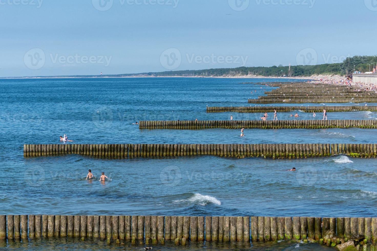 Beach with wooden breakwater. Beautiful seascape. Protection holidaymakers from effects of both weather and longshore drift. photo