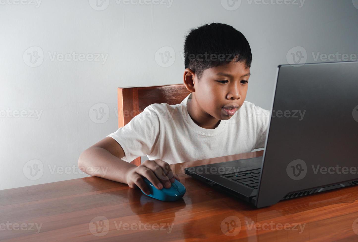 Close up The boy sits staring at the laptop and his hand is holding the mouse. educational concept, educational information search, copy space photo