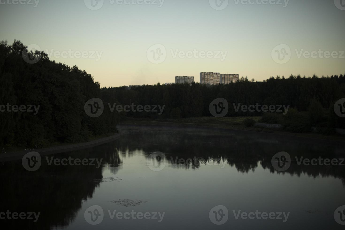 Lake in city. Pond in evening. Natural object in park. Forest reflection in water. photo