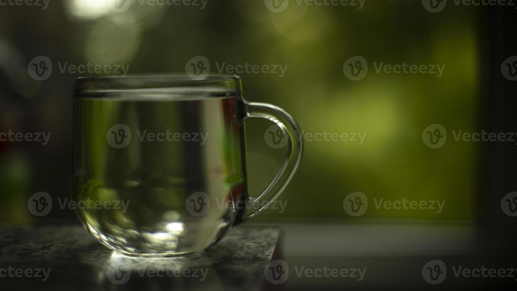 Glass with water on background of window. Water in cup. Transparent drink. photo