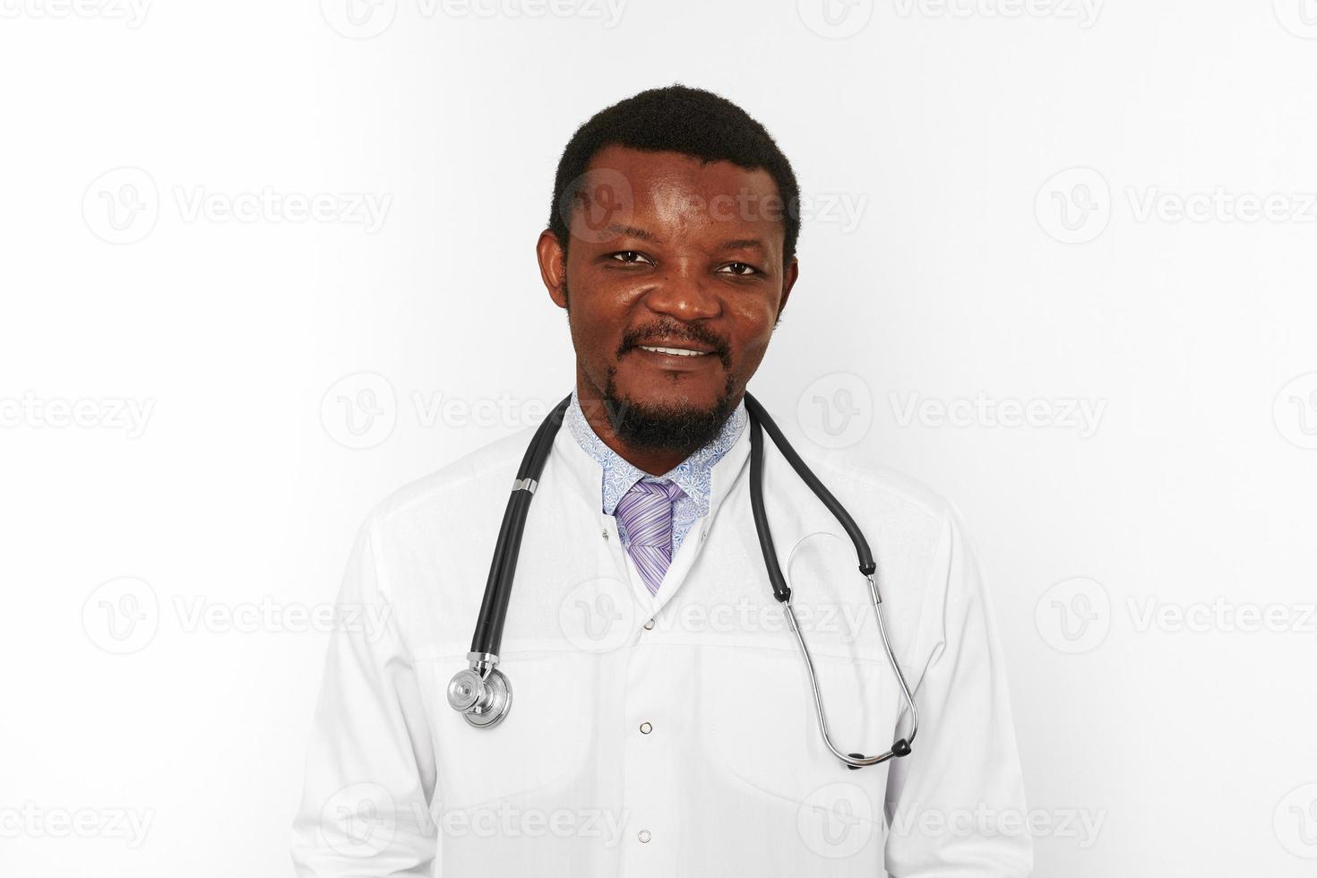 Smiling black bearded doctor man in white coat with stethoscope isolated on white background photo