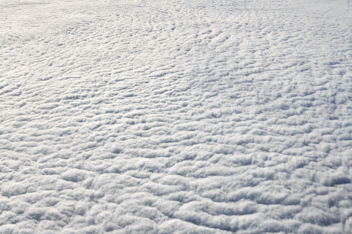 Over clouds top view from aircraft window, thick white blue clouds looks like soft foam photo